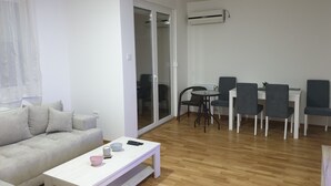 Een moderne woonkamer met een bank, een salontafel, en een eethoek met stoelen en een tafel.