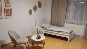 A modern hotel room with a bed, a chair, a small table, and a bedside lamp. - Merci vacation apartment (Niestetal)