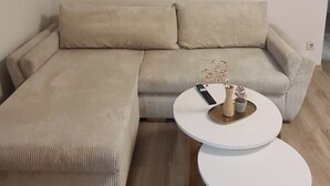 A modern living room with a sectional sofa, a small white coffee table, and three framed artworks on the wall. - Merci vacation apartment (Niestetal)