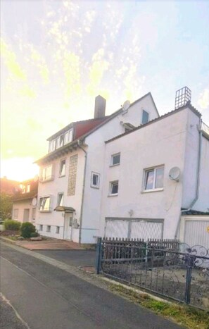 A two-story building with a flat roof, a satellite dish, and a gated entrance. - Merci vacation apartment (Niestetal)