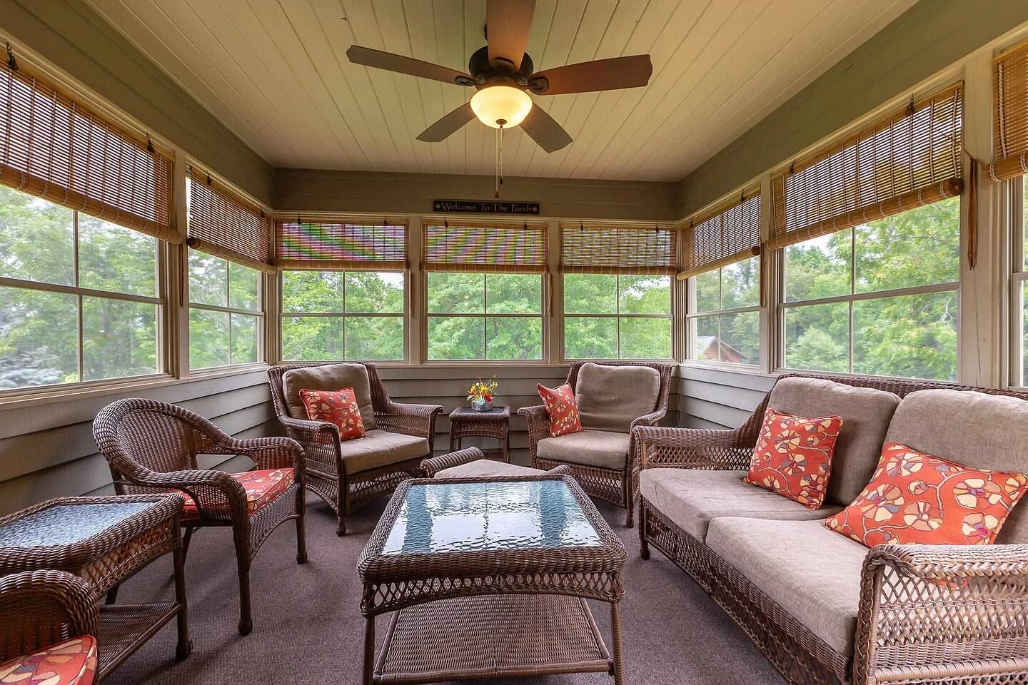 A sunroom with wicker furniture, a ceiling fan, and a view of the outdoors.