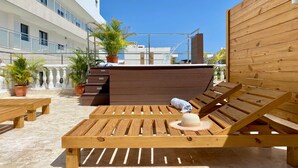 Een houten zithoek met een pooltafel, een hoed en potplanten.