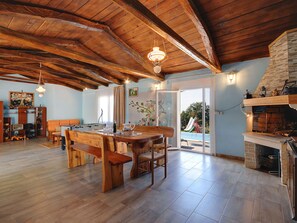 A spacious living area with a wooden ceiling, a dining table, and a fireplace. - House Barat by Interhome (Rovinj/Kanfanar)