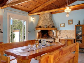 A rustic kitchen with a stone fireplace, wooden furniture, and a view of the outdoors. - House Barat by Interhome (Rovinj/Kanfanar)