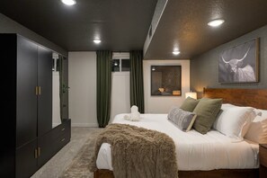 Ein modernes Schlafzimmer mit einem großen Bett, einem dunklen Wandschrank und einem Fenster mit Vorhängen.