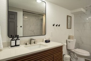 Ein modernes Badezimmer mit einem großen Spiegel, zwei Waschbecken, einer Toilette und einer Duschkabine.