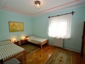 A room with two single beds, a wooden floor, a radiator, a window with a white curtain, and a wall-mounted light fixture. - Apartment 926 by Interhome (Bokordici)