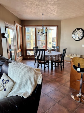 Un coin repas comprenant une table ronde, des chaises, un lustre et une horloge murale.