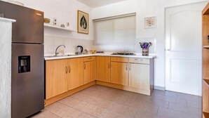 Una cocina moderna con armarios de madera, un refrigerador de acero inoxidable, un fregadero y una estufa.