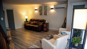Un salon avec un canapé, un fauteuil et une petite table sur laquelle se trouve une lampe.