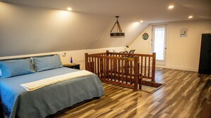 Une chambre à coucher avec un lit, un plancher en bois, un bureau et une chaise.