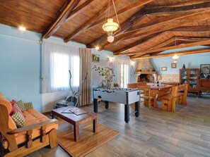 Un salon chaleureux avec un baby-foot, un canapé et un coin repas doté de meubles en bois.