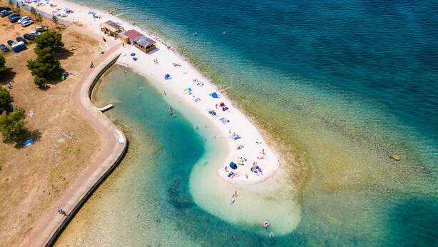 An aerial view of a beach with clear water, a curved shoreline, and a few beach umbrellas. - Villa Valbandon by Interhome (Fažana)