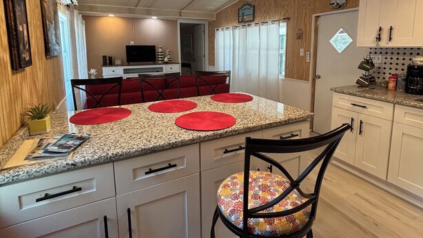 Cozinha com ilha central, espaço de refeições com cadeiras e geladeira.