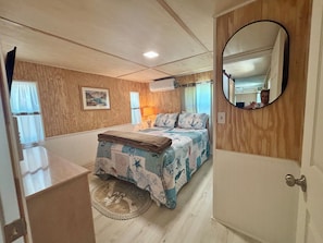 Un dormitorio con cama, espejo, lámpara y puerta.