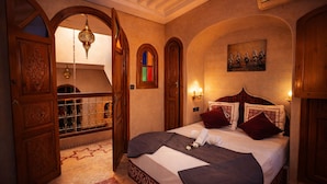 Ein traditionell eingerichtetes Zimmer mit einem Bett, Holztüren und einem Gemälde an der Wand.
