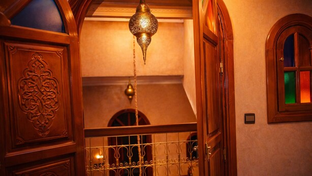 A wooden interior with ornate carvings, a hanging lantern, and a barred window. - Riad 16 Dar and Pool (Marrakech)
