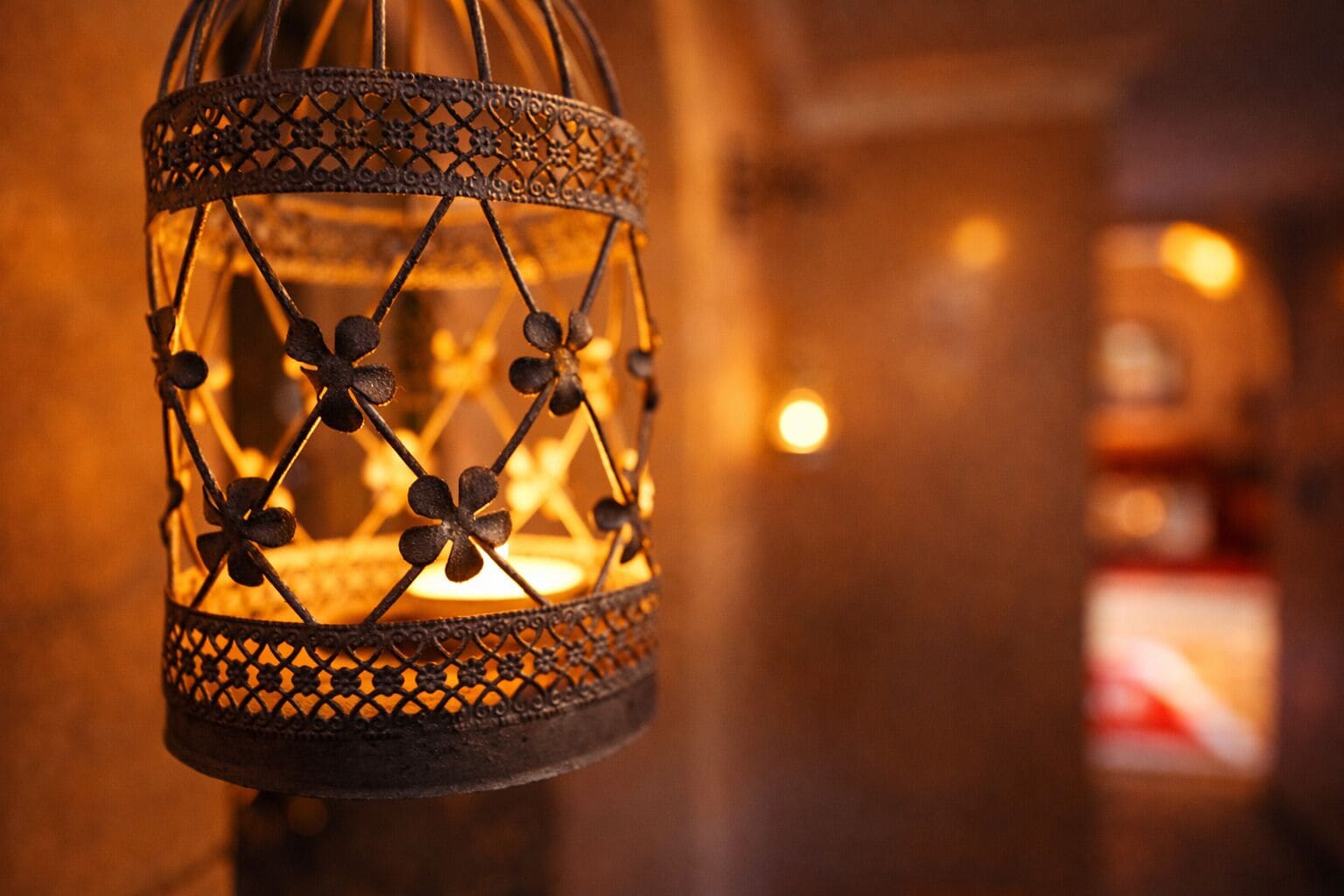 A close-up of a decorative metal lantern with intricate patterns and a lit candle inside.