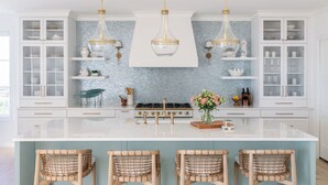 A modern kitchen with white cabinetry, a central island with bar stools, and pendant lighting.