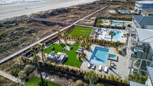 An aerial view of a resort with a pool area, a beach, and a boardwalk.