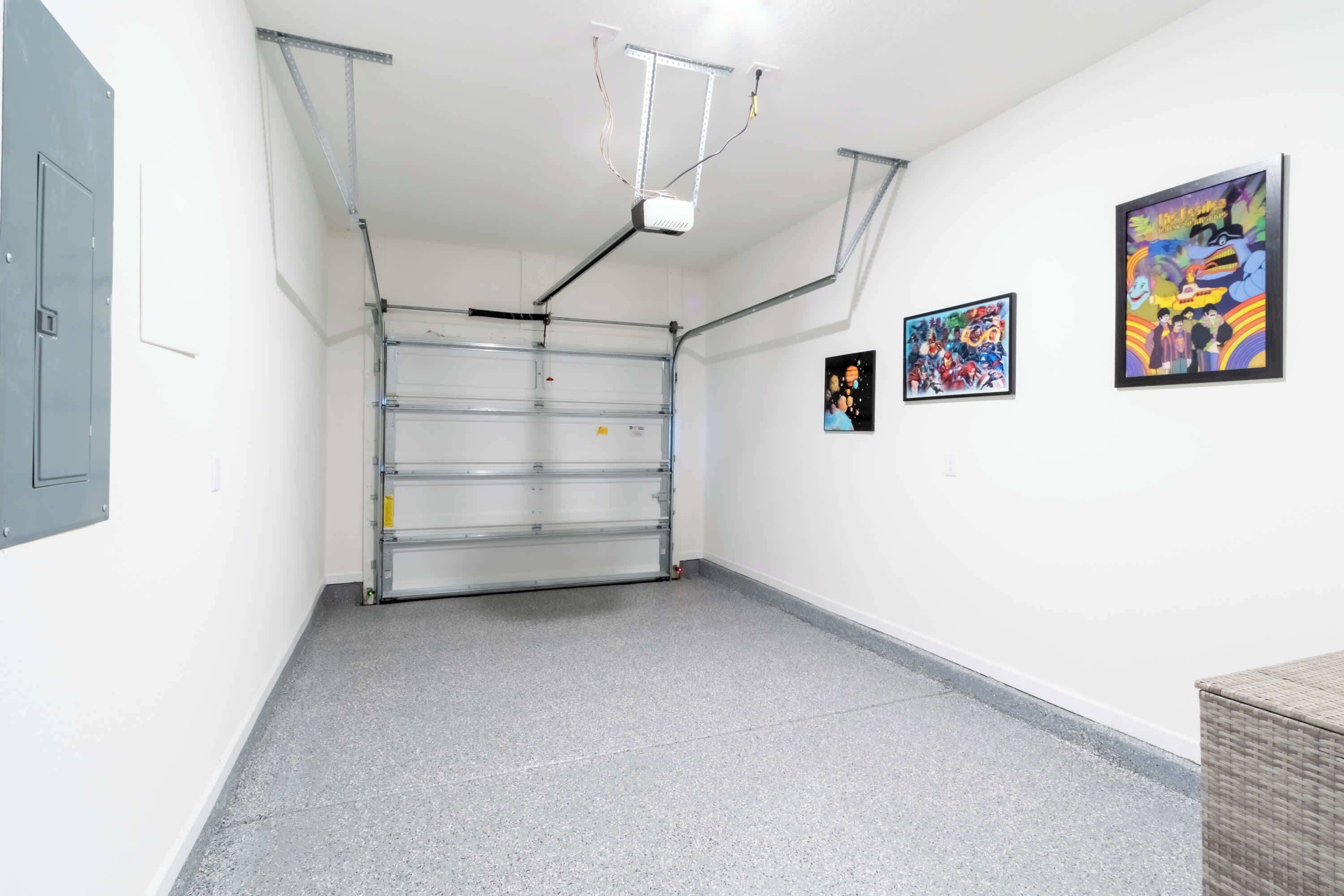 Een schone, lege kamer met een grijze vloer, een deur met metalen frame en twee kunstwerken aan de muur.