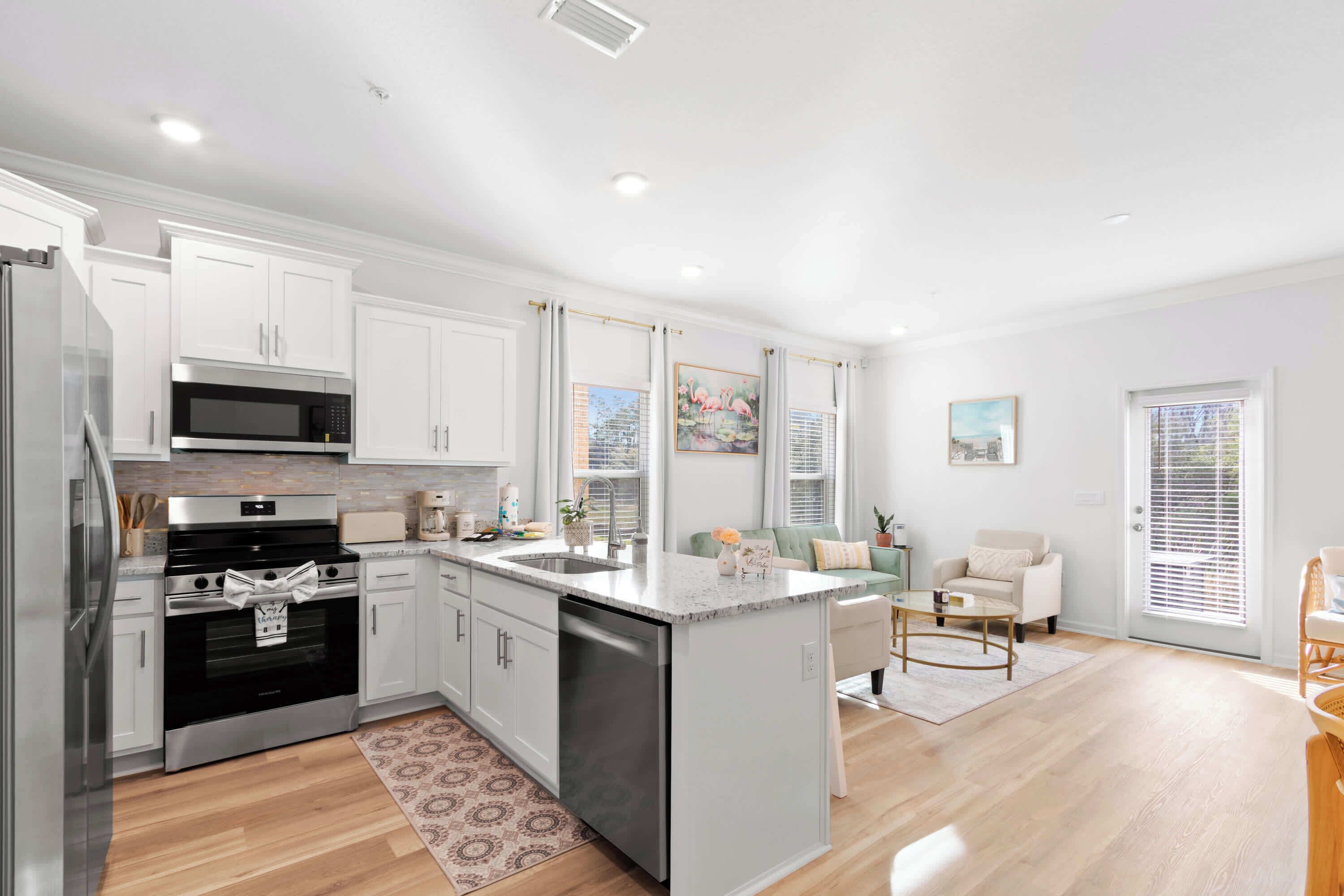 A modern kitchen with white cabinetry, stainless steel appliances, and a central island.