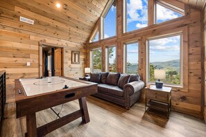 A wooden interior with a pool table, a sofa, and large windows offering a view of the outdoors. - 3 King Ensuite ~MTN Views~Gameroom~Hot Tub~Firepit (Sevierville)