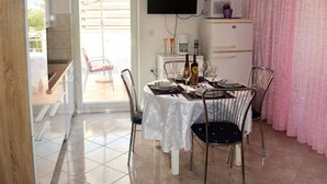 A dining area with a table set for two, a television mounted on the wall, and a pink curtain. - Apartment 1337 by Interhome (Labin)