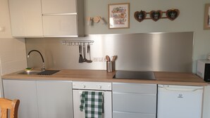 Eine moderne Küche mit weißen Schränken, einer Edelstahl-Dunstabzugshaube, einem eingebauten Geschirrspüler und einer Arbeitsplatte mit einem Toaster.