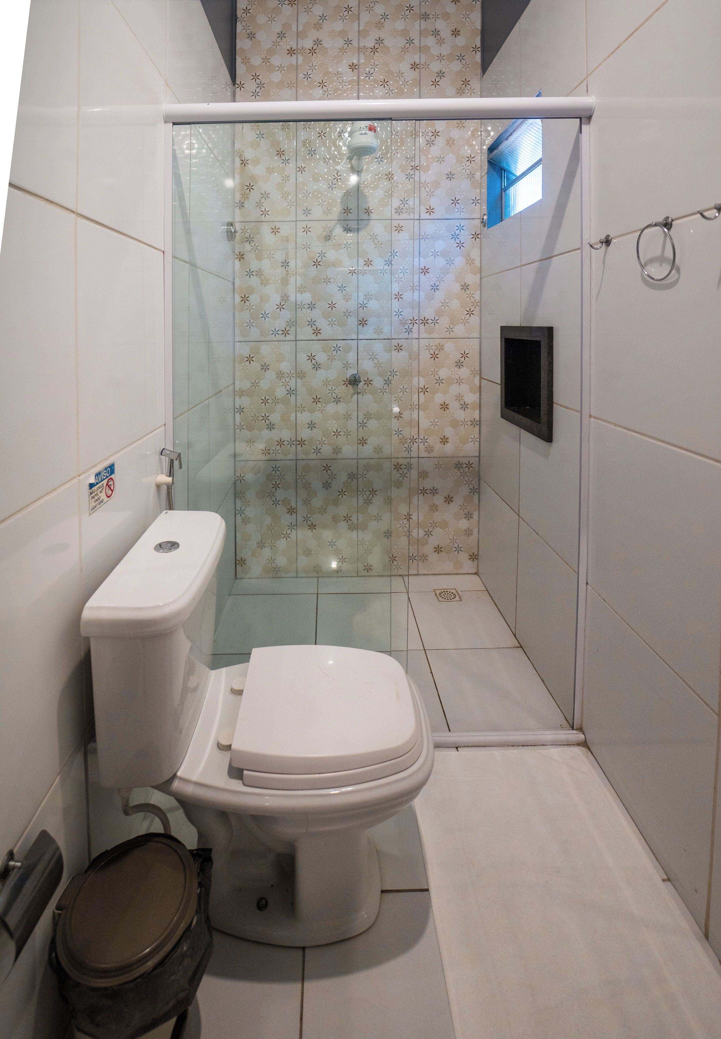 Un baño con inodoro, cabina de ducha y suelo de baldosas.