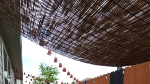 Un bain à remous surmonté d’une pergola en bambou, entouré d’une clôture en bois et d’un petit jardin.