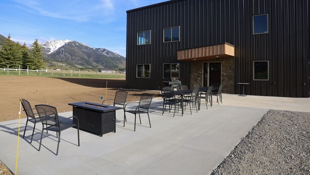 Un bâtiment moderne doté d’un patio aménagé avec des espaces de détente en plein air et offrant une vue sur les montagnes.