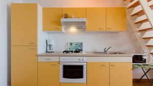 Cocina compacta con gabinetes amarillos, estufa blanca y cafetera.
