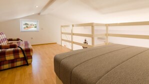 Un dormitorio con una cama, una silla, un separador de madera y un cuadro en la pared.