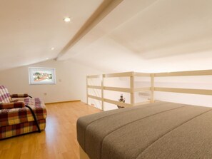 Ein Schlafzimmer mit einem Bett, einem Sessel, einer Holzwand und einem gerahmten Bild an der Wand.