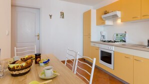 Cocina compacta con mesa, sillas y electrodomésticos básicos.