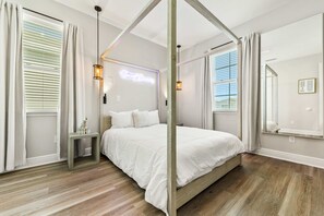 A bedroom with a canopy bed, bedside tables, a neon sign, and large windows with curtains. - New 5BR - Close To Disney - Private Pool (Kissimmee)