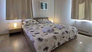 A bedroom with a bed, curtains, a nightstand, a wall-mounted light, and a framed picture. - Villa Mugeba I by Interhome (Dracevac)