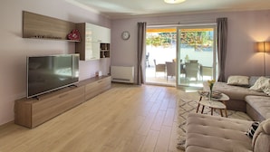 A modern living room with a flat-screen TV, wooden entertainment unit, sofa, and a dining area with chairs and a table. - Villa Mugeba I by Interhome (Dracevac)