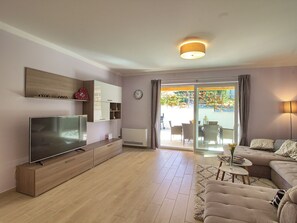 A modern living room with a flat-screen TV, wooden entertainment unit, sofa, and a dining area with chairs and a table. - Villa Mugeba I by Interhome (Dracevac)
