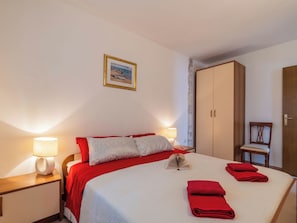 Ein Hotelzimmer mit einem Bett, Nachttischlampen, einem Kleiderschrank und einem gerahmten Bild an der Wand.