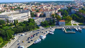 An aerial view of a city with a prominent historical building, a marina with boats, and a mix of residential and commercial buildings. - Apartment 1510 by Interhome (Pula/Krnica)