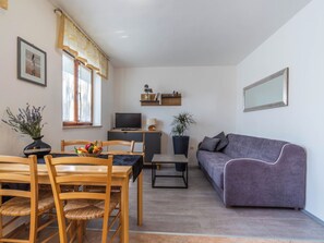 A living room with a sofa, a dining table with chairs, a TV, and a plant. - Apartment 1510 by Interhome (Pula/Krnica)