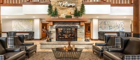 A lobby with a fireplace, leather sofas, a coffee table, and a 'Welcome' sign above the fireplace.