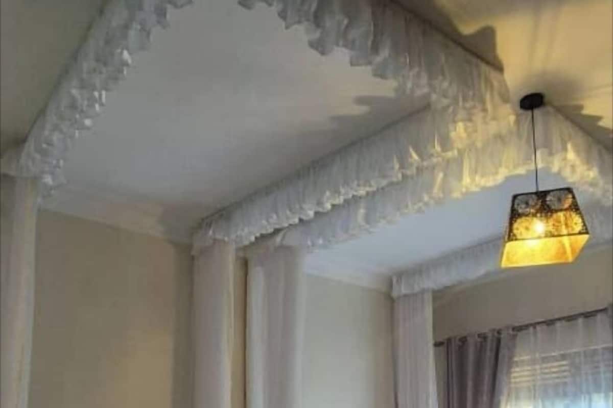 A hotel room with two beds, a canopy bed, and a hanging light fixture.