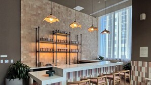 Eine moderne Bar mit einer Marmorarbeitsplatte, hängenden Pendelleuchten und einem Schachbrettmuster auf dem Boden.