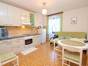 Eine kleine Küche mit Gasherd, Backofen und Kühlschrank. Es gibt einen Essbereich mit Tisch und Stühlen.