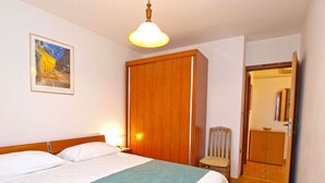 Ett hotellrum med en säng, en stol, en garderob och en tavla på väggen.