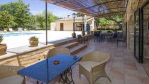 Eine überdachte Terrasse im Freien mit Pool, Korbmöbeln und Blick auf den Pool.