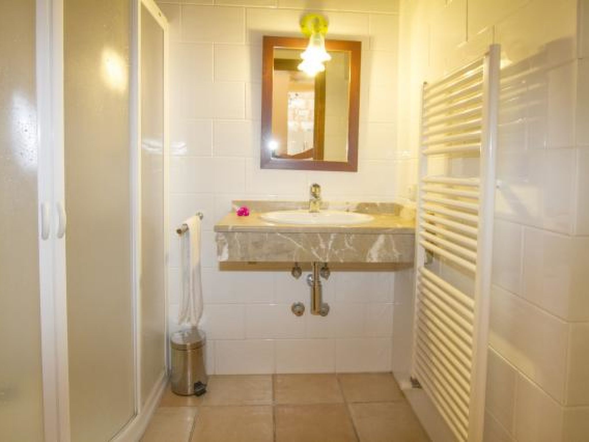 Casa de banho com lavatório, espelho, suporte para toalhas e zona de duche.